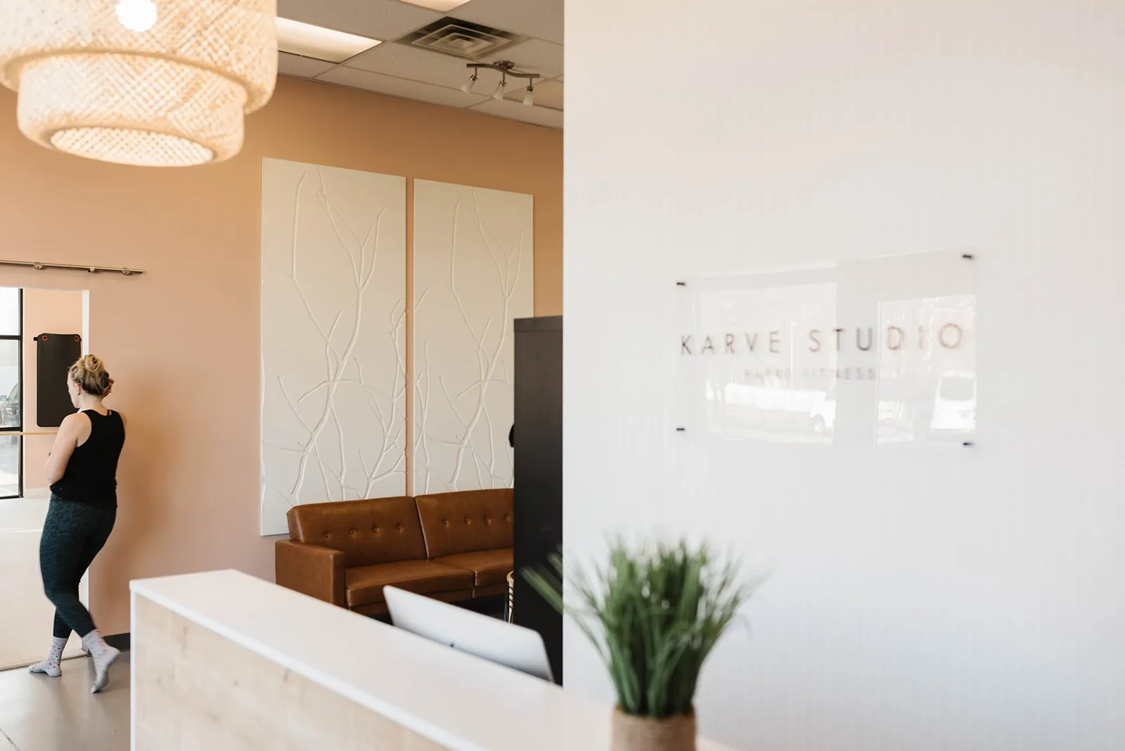 The Karve front desk with a woven pendant light, leather sofa and peach walls